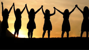 women holding hands backlit by the sunset